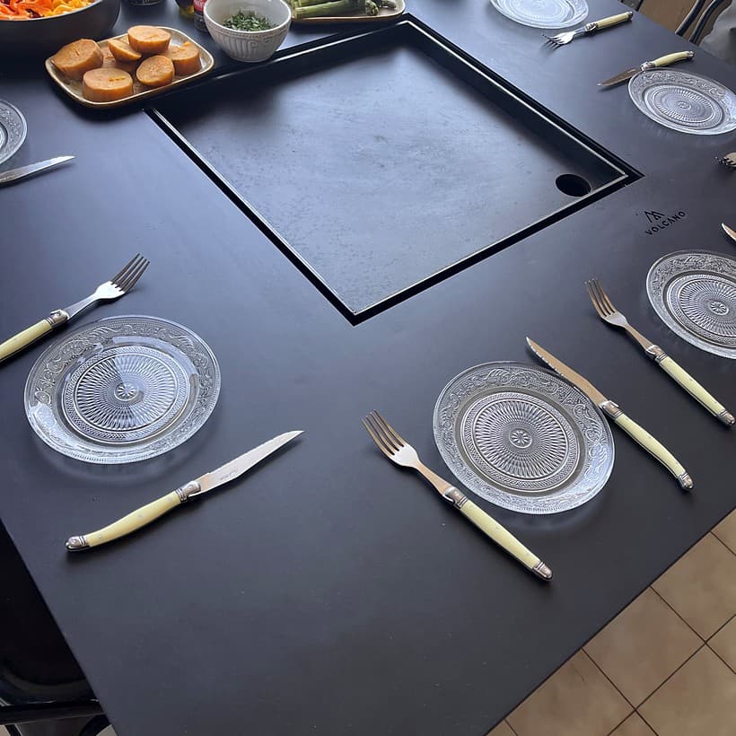 Personas cocinando y compartiendo alrededor de una mesa Volcano, escena 1
