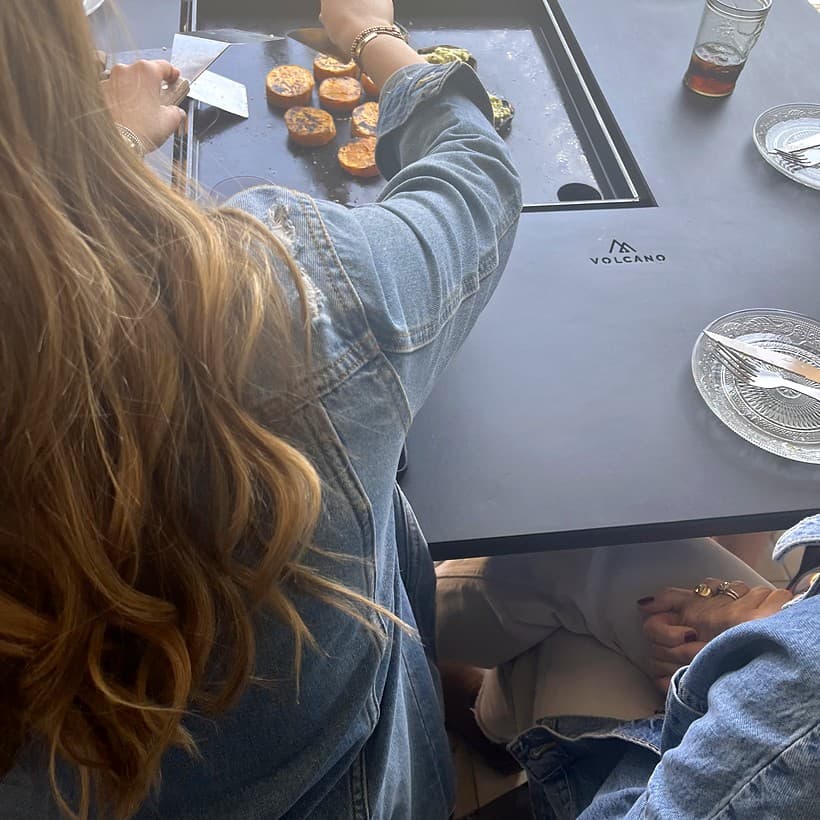 Personas cocinando y compartiendo alrededor de una mesa Volcano, escena 3